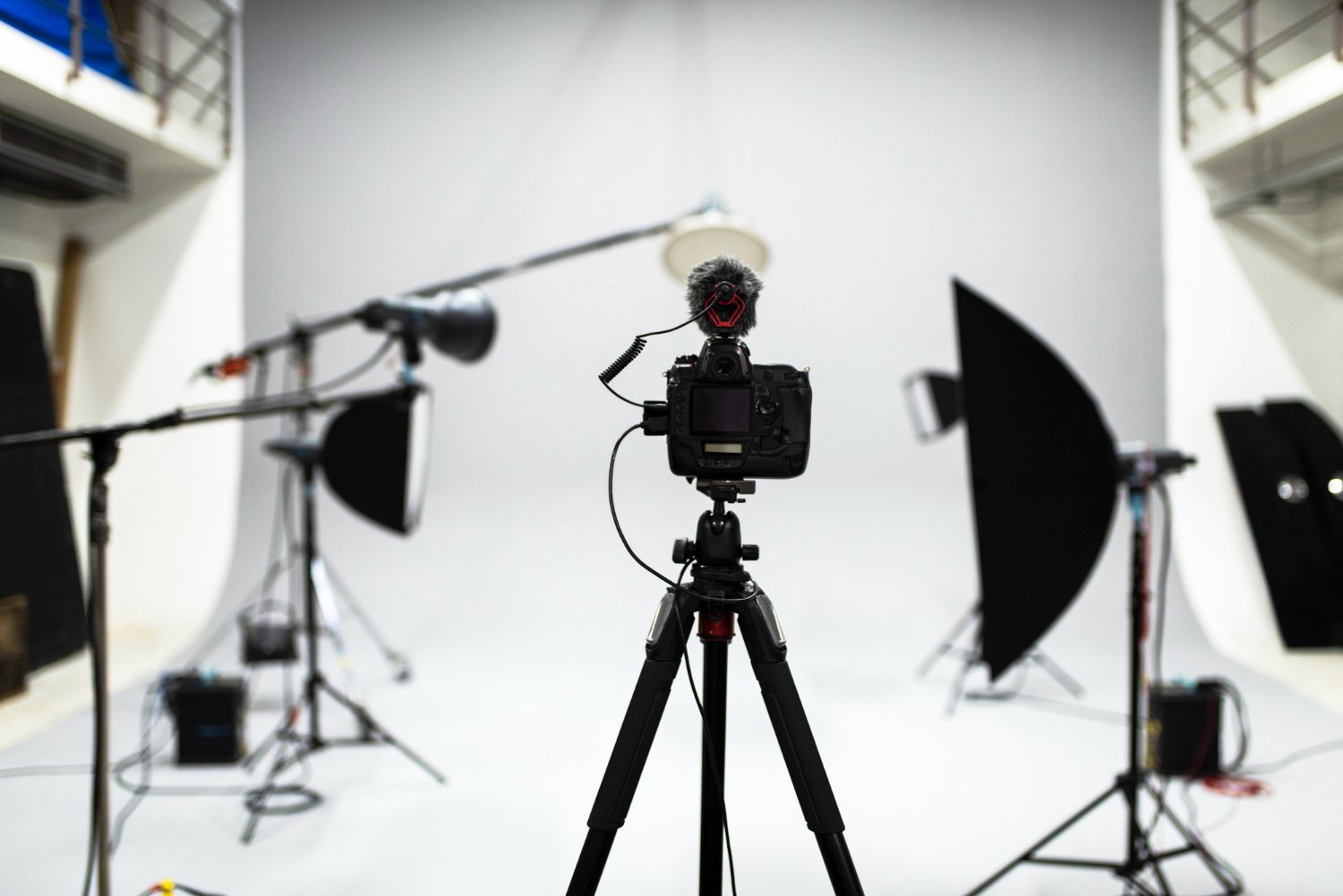 Equipo de grabación de vídeo con luces de estudio y fondo blanco, técnica utilizada en producciones audiovisuales de alta calidad.