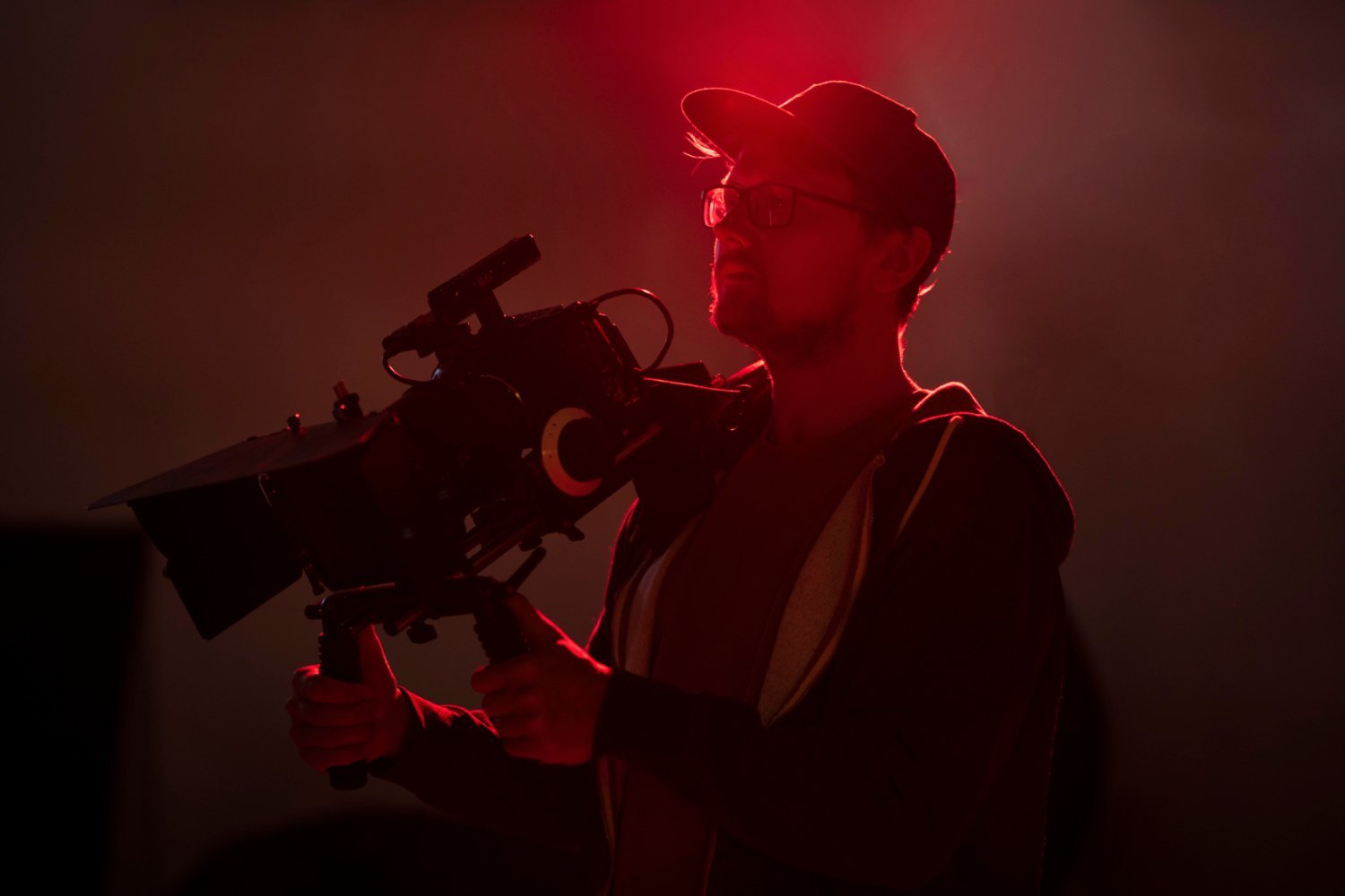 Anxo Casal Parareda Realizador de vídeo con cámara profesional en set de filmación con iluminación roja.